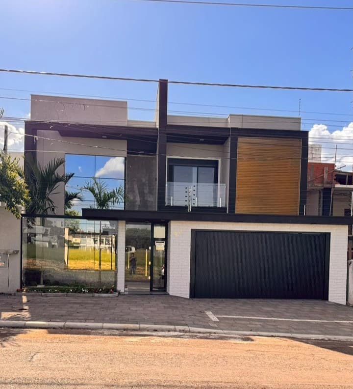 Fachada residencial com muro em vidro e portão de alumínio, destacando a elegância e modernidade dos materiais utilizados pela Vidraçaria Nogueira.